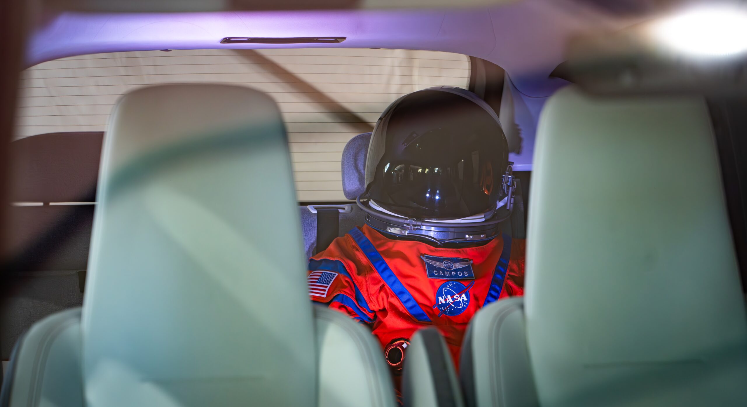 Манекен в костюме астронавта миссии Artemis на заднем сиденье электромобиля