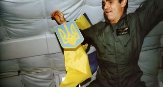 Леонід Каденюк тримає герб України поряд з прапором у невагомості на борту шатла Columbia