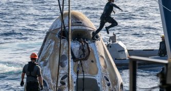 Рятувальні команди працюють біля капсули SpaceX Dragon Freedom, що гойдається на хвилях Тихого океану після приводнення.